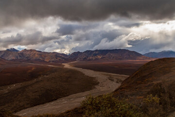 dramatic autumn landscape of snowcapped mountain ranges and peaks inside DEnali National park .