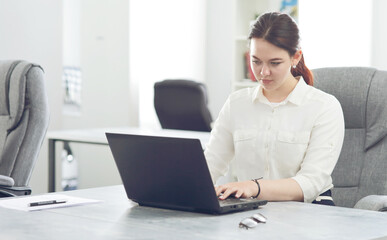 Young attractive business woman working in office smiling looking into laptop