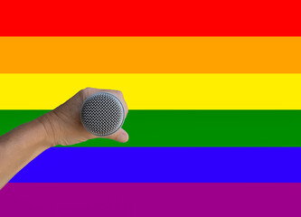 hand holding a microphone with gay pride flag background
