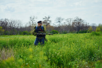 Airsoft player in camouflage military uniform holds a rifle in his hands