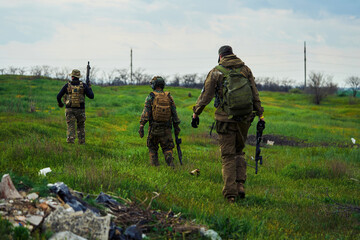 Soldiers with weapons in their hands are walking across the field