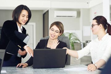 Three young successful business women in the office, together, happily working on a project