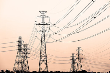 silhouettes of high voltage towers on orange background