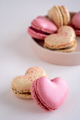 A group of heart-shaped French macaron cookies on round plate for Valentines day