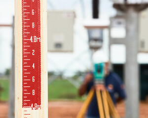 topographic scale with topographer with theodolite back out of focus measuring terrain, distance...