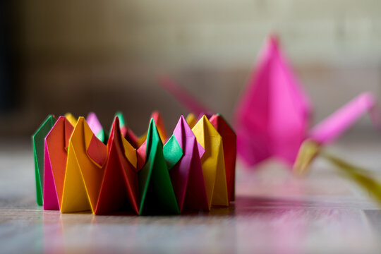 colorful modular origami in the shape of a kaleidoscope with two cranes in the background