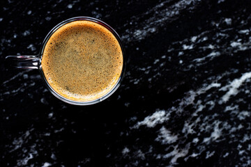 Una taza de café espresso en mesa de mármol negro. Vista cenital. Espacio para texto