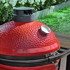 Big Ceramic Red Egg BBQ Grill. Kamado Barbecue Charcoal Grill For Cookout Food. Ceramic Barbeque Grill And Smoker On The Backyard Lawn Or Restaurant Outdoor Terrace.