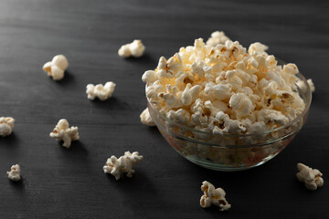 Palomitas de maíz en un recipiente con palomitas tiradas en la mesa de color negro