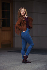 Young fashion woman in leather fringe suede jacket and dark blue jeans