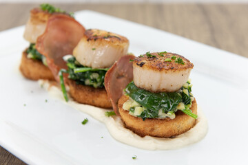 Seared Scallops sitting atop a bed of spinach served as a threesome for your seafood appetite