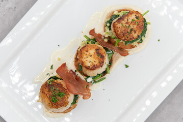 Overhead view of seared Scallops sitting atop a bed of spinach served as a threesome for your seafood appetite