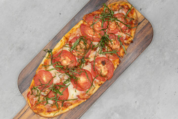 Overhead view of margarita flatbread pizza topped with slices of tomato, cheese on delicious baked flatbread crust