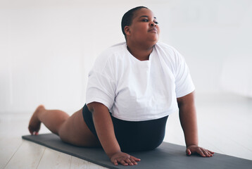 young plus size woman exercising on sport mat at home, pushups from the floor