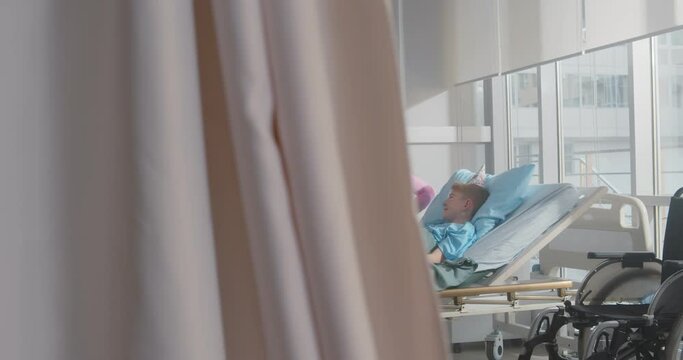 Mother and father visiting sick son in hospital ward and celebrating birthday together