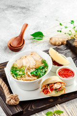 Asian noodle soup. Ramen with chicken, tofu, and vegetables on white plate on concrete background. Close up. 
