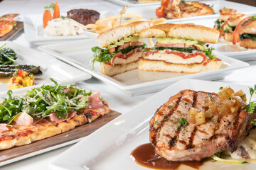 Huge selection of different restaurant plates of food with a delicious pork chop up in front