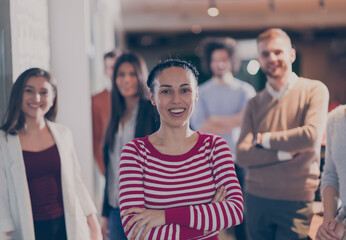 Beautiful Hispanic or modern Muslim businesswoman looking at camera and smiling coworkers diverse...