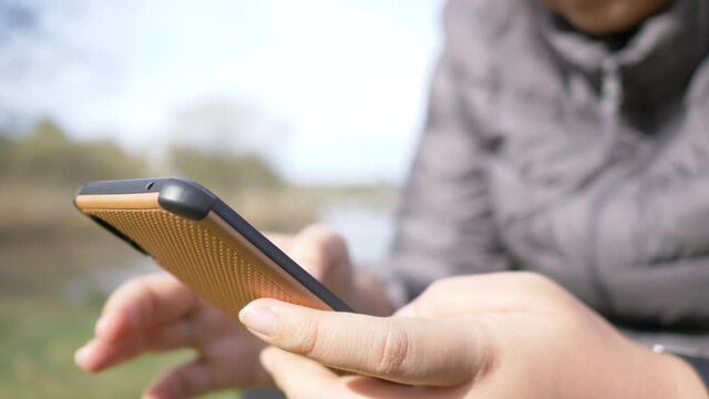 Close up hands of Asian woman sitting and using smartphone to look a photo taken and search for digital map in the forest, Stuning view outdoor on the weekend. Go camping