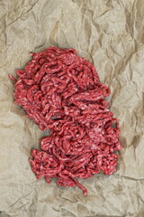 Raw Minced Meat On Brown Craft Or Baking Paper, Isolated On Black Background. Top View of Fresh Ground Beef Isolated on Black. Uncooked Minced Beef Meat.