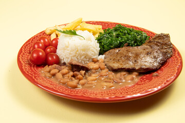 typical Brazilian basic dish with rice, beans, steak, french fries, braised cabbage and tomato