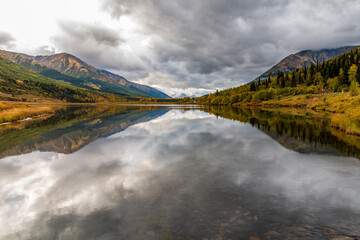 autumn foliage and mounter reflection on a tranquil lake in kenai peninsula , alaska