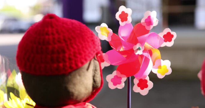 A slow motion of moving colorful windmills with Jizo statue daytime closeup
