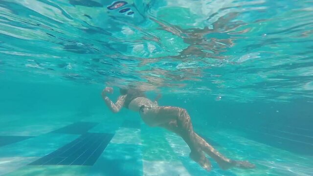 young girl swimming in underwater bikini in the pool