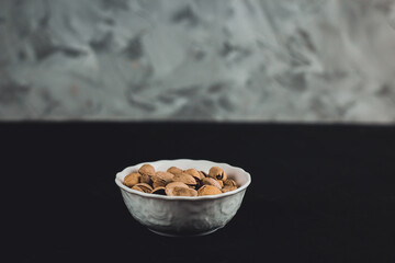 Pistachios in a white plate on a dark background