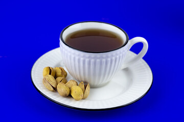Pistachios in a white plate on a blue background