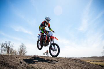 Obraz na płótnie Canvas Motocross rider lands a jump on a race track.