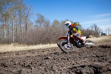 Motocross rider rides an orange dirt bike on a race track.