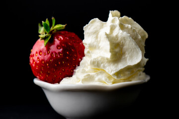 bowl of strawberries and cream shot with a macro lens with a black background 