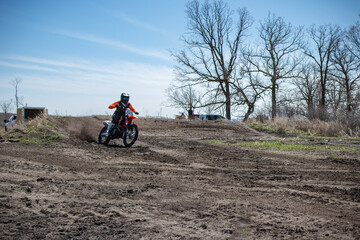 Fototapeta na wymiar Dirt biker takes off out of a corner spewing lots of dirt and debris.
