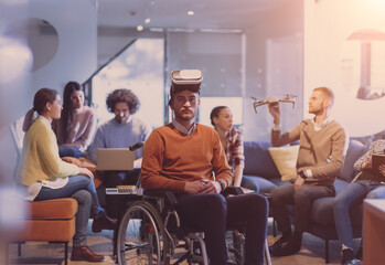 Disabled businessman in a wheelchair at work in modern open space coworking office with team using virtual reality googles drone assistance simulation