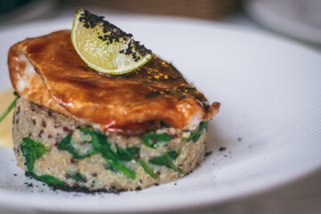 Partially blurred plate with quinoa platter, sauce, pike perch, lime