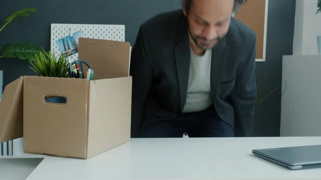 New employee is bringing box with belongings to workplace and working with laptop smiling enjoying career opportunities. People and employment concept.