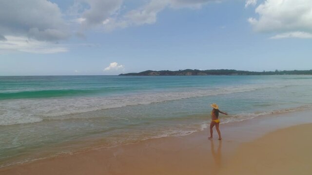 Tropical island beach and carefree woman walking on the sea sand