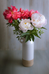 Pretty bouquet of white and red peonies in a ceramic vase.