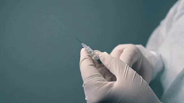 manos con jeringa expulsando liquido 