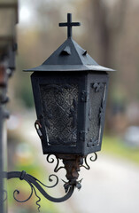 Metal grave lantern with candle. Cemetery decoration.  
Christian cemetery. Old lantern with a cross. 
All Saints' Day.