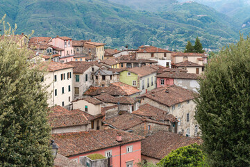Fototapeta na wymiar Old tiled roof. Beautiful roofs in the medieval town of Barga in Tuscany in the mountains of Italy. Beautiful mountains outside the city. Old houses are ledges.