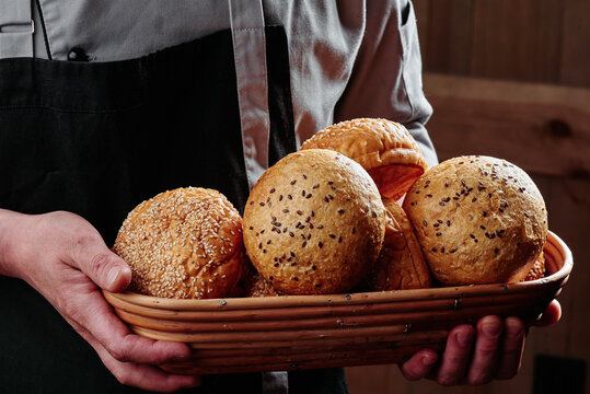 baker holds burger buns in a basket. series of photos