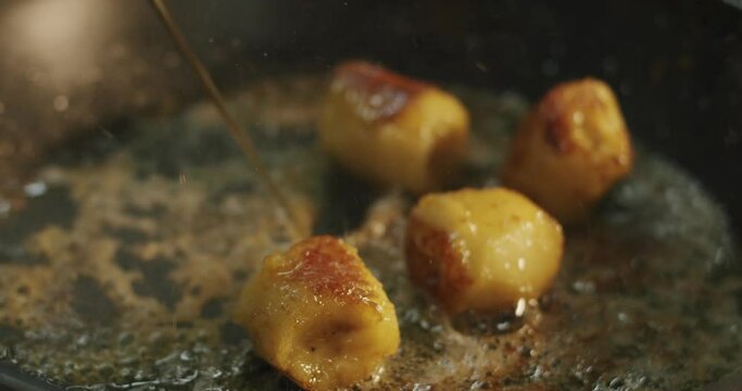 The chef adds cooking alcohol to the roasting banana chunks and sets it on fire