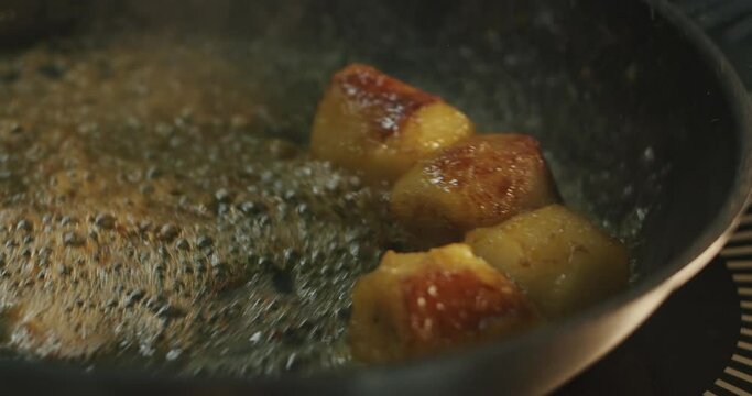 Pieces of a ruddy banana are fried in hot oil and cognac until golden brown