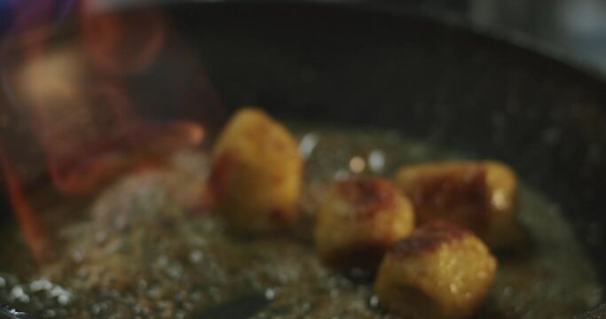 The cook sets fire to culinary alcohol (cognac) in a hot frying pan with banana pieces and butter in slowdown