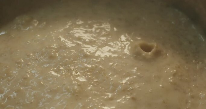 Cooked porridge boils and gurgles close-up in slow motion