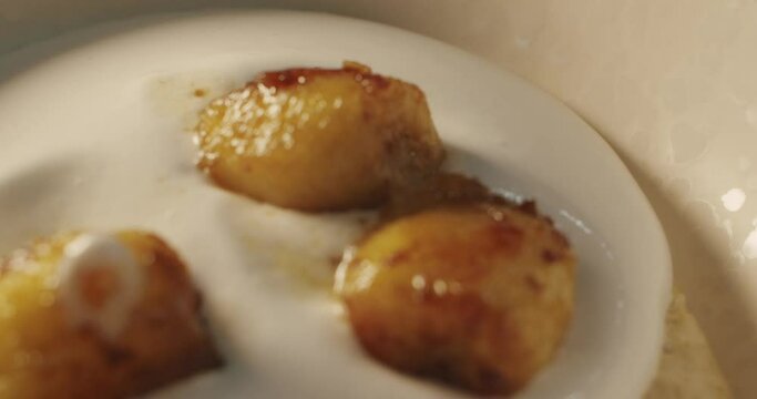 The cook adds the banana fried in cognac to the white coconut mousse cream