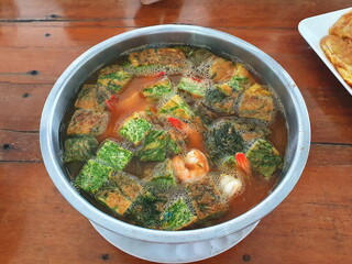 Climbing Wattle Omelette with Fresh shrimp in Sour Soup Served on a stainless steel cup on a wooden table. It's a popular local dish with various herbs in the broth.Eat with hot steamed rice
