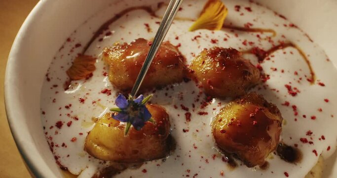 The chef decorates a delicate coconut banana dessert with edible flowers
